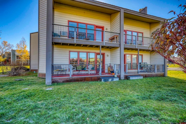 rear view of house with a lawn, a balcony, and a deck