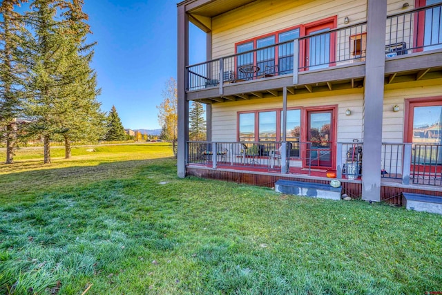 rear view of house featuring a wooden deck and a yard