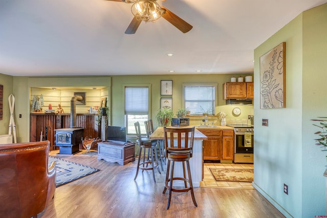 kitchen with a wood stove, a kitchen bar, light hardwood / wood-style floors, and stainless steel range oven