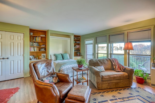 living area featuring built in shelves, light wood-type flooring, and a wealth of natural light