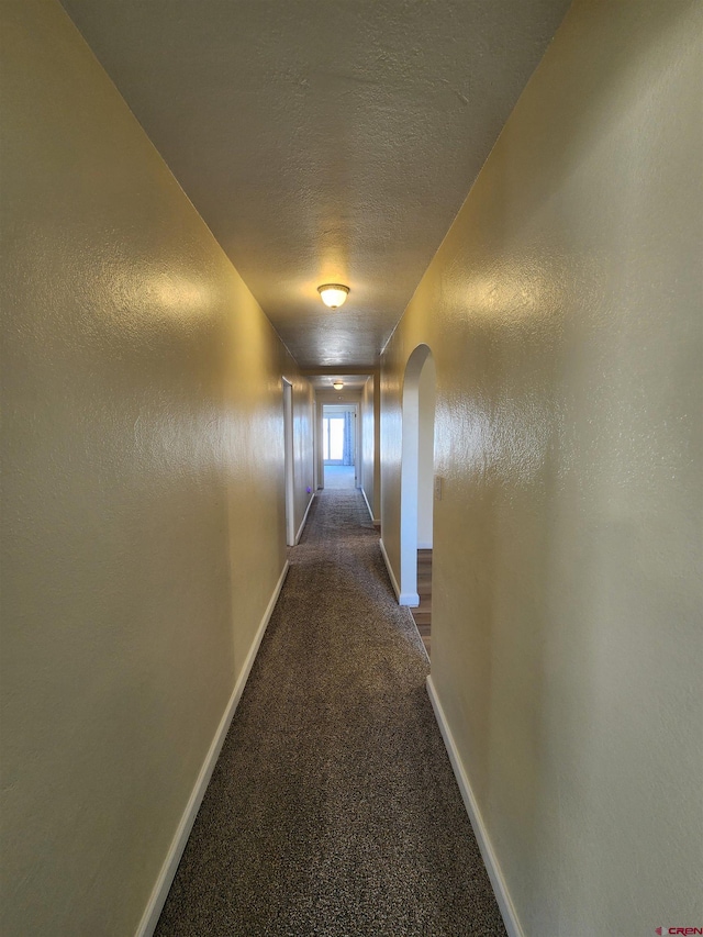 hall with a textured ceiling and carpet floors