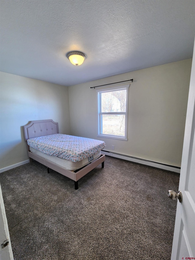 carpeted bedroom with a textured ceiling and a baseboard heating unit