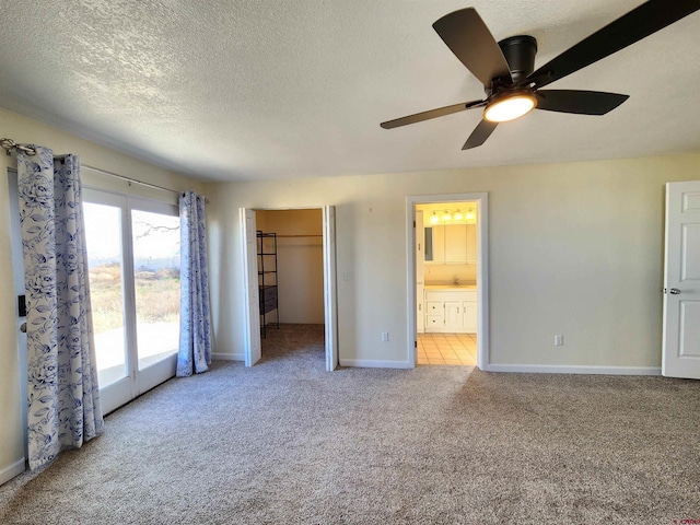 unfurnished bedroom with a closet, a walk in closet, light colored carpet, and ceiling fan