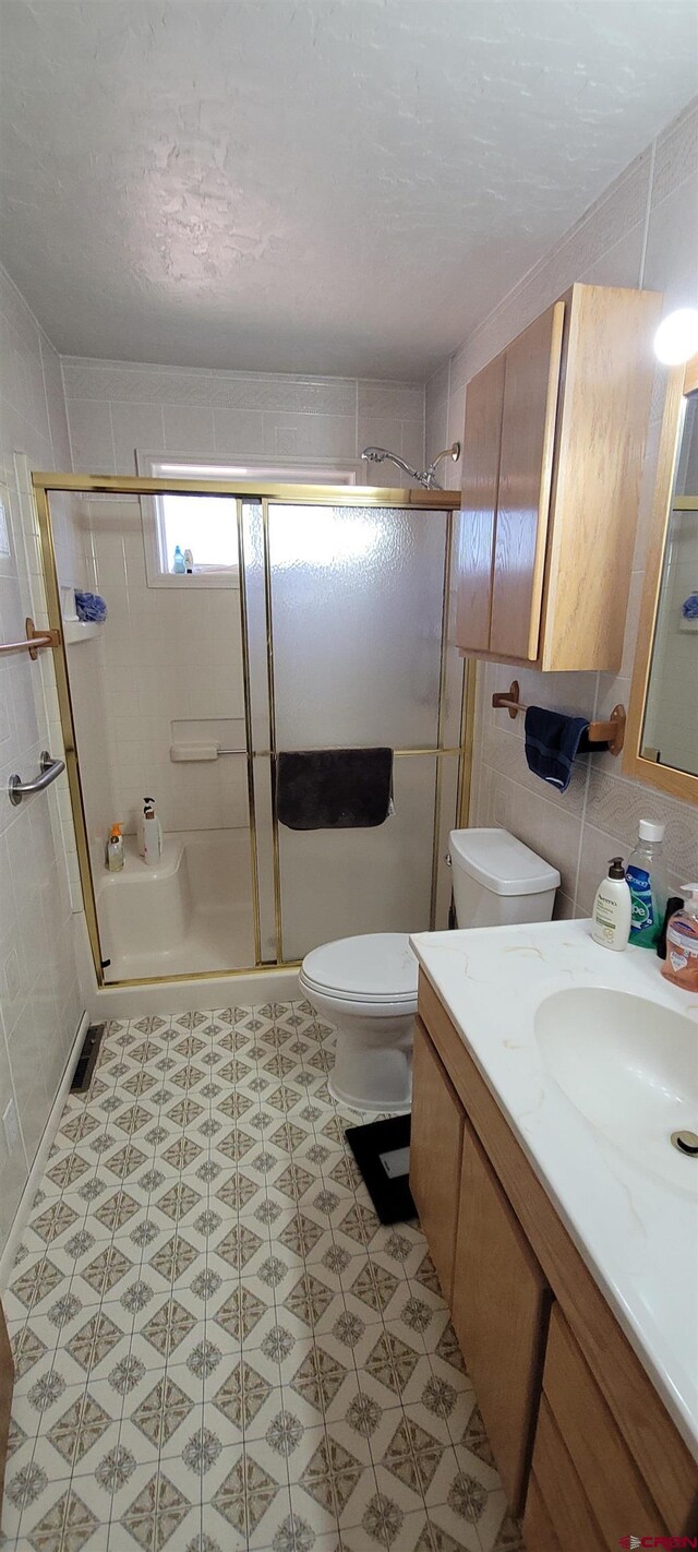 9966 Rd 7, Dove Creek, CO 81324 - bathroom with a stall shower, toilet, vanity, and tile walls
