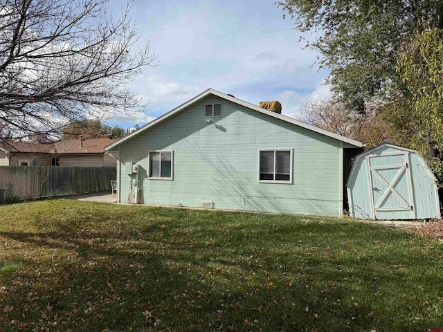 rear view of house with a lawn and a storage shed