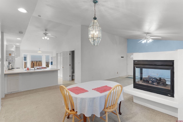 carpeted dining space with a multi sided fireplace and lofted ceiling