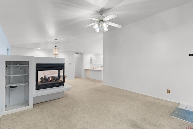 unfurnished living room with a multi sided fireplace, vaulted ceiling, light colored carpet, and ceiling fan