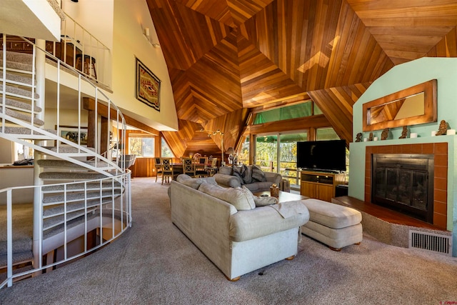 carpeted living room with wooden ceiling, a tile fireplace, wooden walls, and high vaulted ceiling