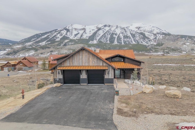77 Coyote Ridge Rd, Crested Butte, CO 81224 - view of front of house featuring a chimney, metal roof, an attached garage, a mountain view, and driveway