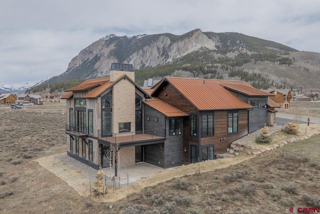 77 Coyote Ridge Rd, Crested Butte, CO 81224 - back of property with a standing seam roof, a chimney, a patio area, a garage, and a mountain view