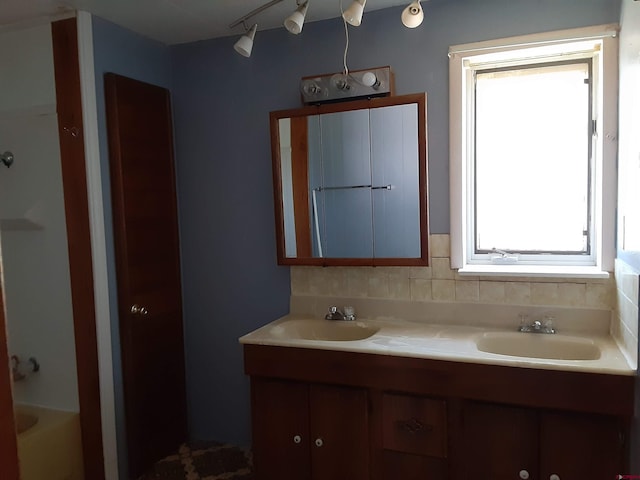 bathroom with a tub, vanity, and backsplash