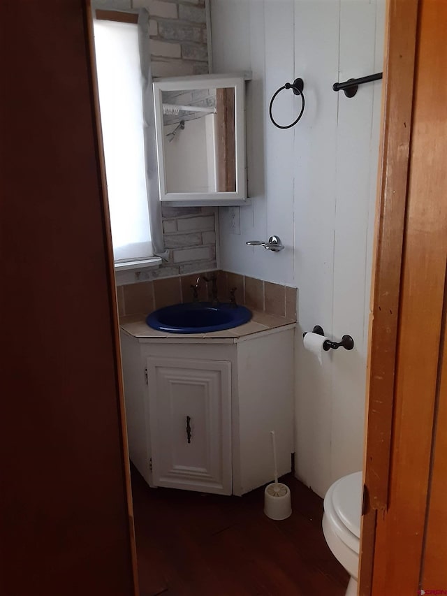 bathroom with decorative backsplash, vanity, hardwood / wood-style flooring, and toilet