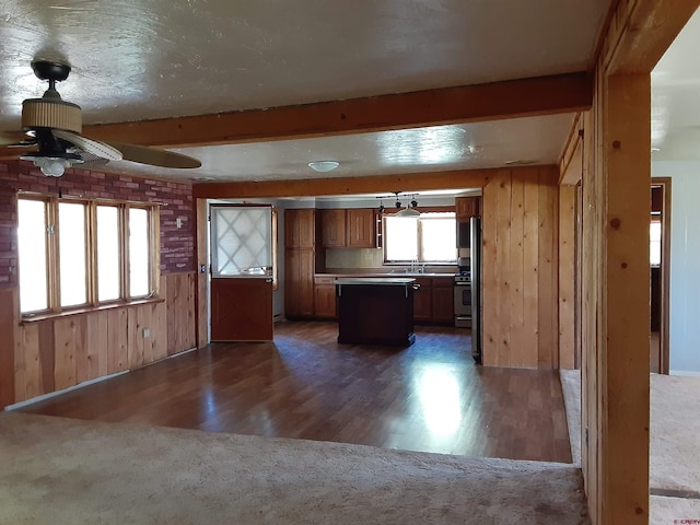 kitchen featuring dark hardwood / wood-style flooring, a kitchen island, beamed ceiling, and wooden walls