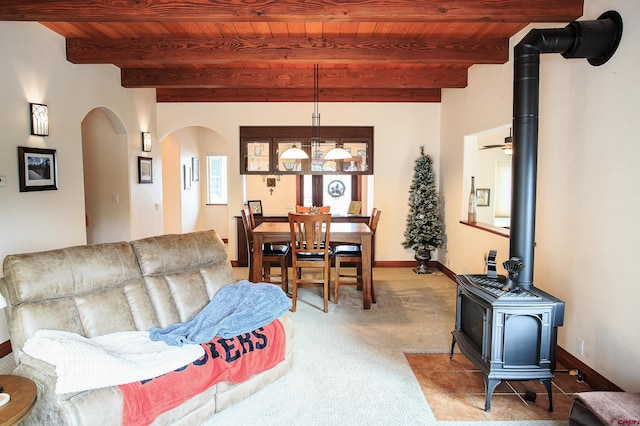 carpeted living room featuring a wood stove, beamed ceiling, and wooden ceiling