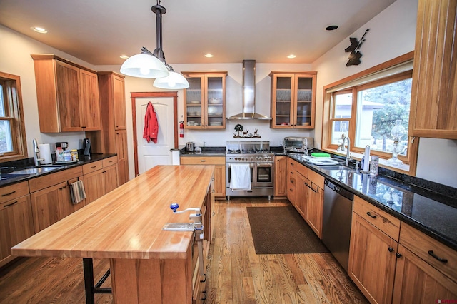 kitchen featuring stainless steel appliances, hardwood / wood-style flooring, wooden counters, wall chimney exhaust hood, and pendant lighting