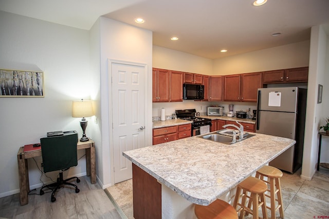 kitchen with a kitchen breakfast bar, appliances with stainless steel finishes, sink, and a center island with sink