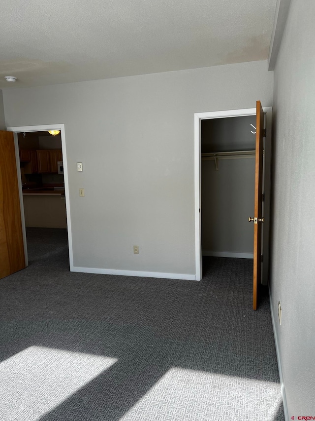 unfurnished bedroom featuring a textured ceiling, a closet, and dark carpet