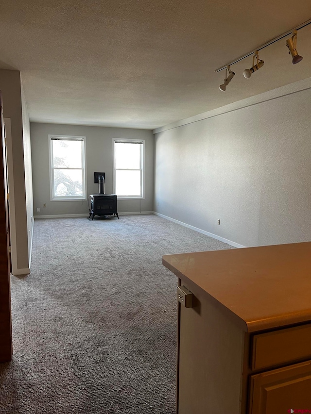 unfurnished living room with a textured ceiling, light carpet, and rail lighting