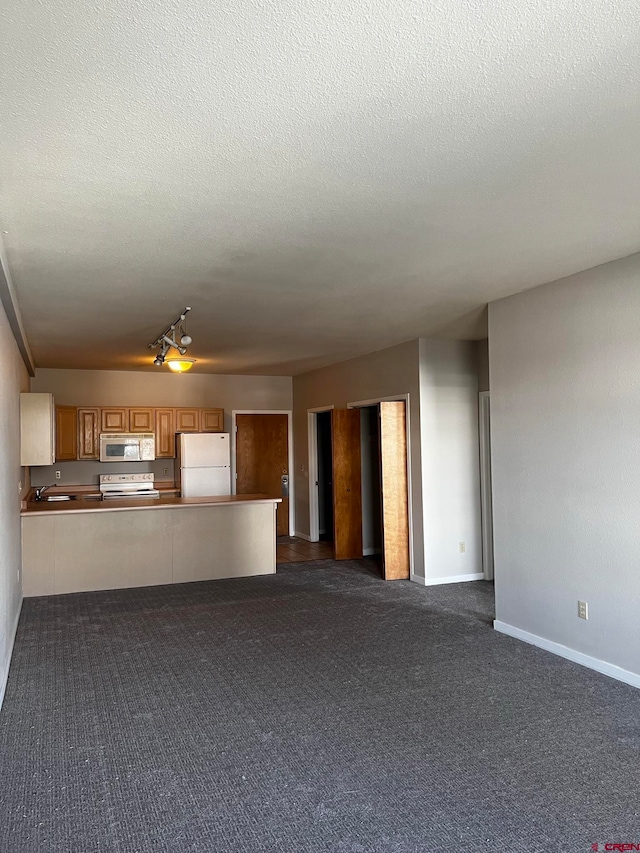 unfurnished living room featuring sink, a textured ceiling, and dark carpet