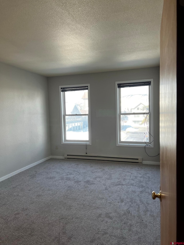 empty room featuring baseboard heating, a textured ceiling, and carpet floors