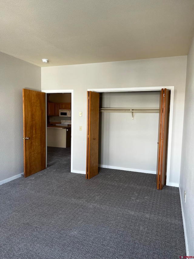 unfurnished bedroom with a closet and dark carpet