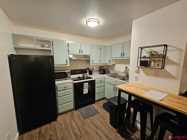 kitchen featuring green cabinets, sink, black appliances, a textured ceiling, and light wood-type flooring