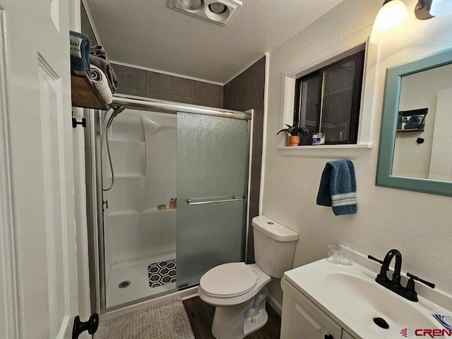 bathroom with vanity, a textured ceiling, toilet, and a shower with shower door