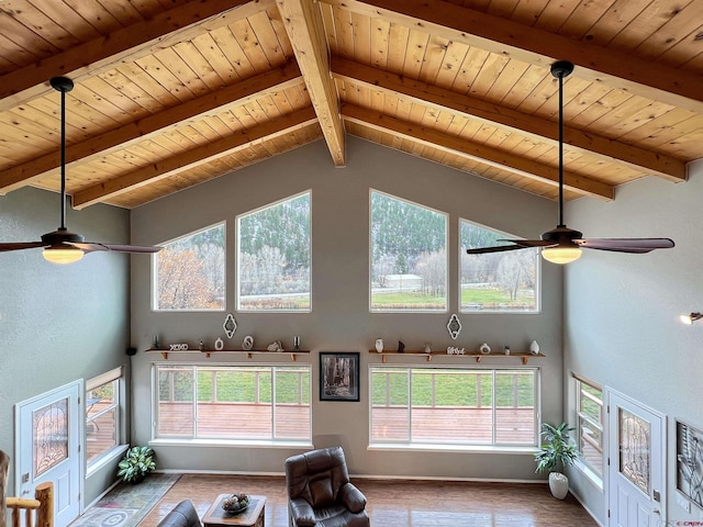 unfurnished living room with vaulted ceiling with beams, ceiling fan, hardwood / wood-style floors, and plenty of natural light