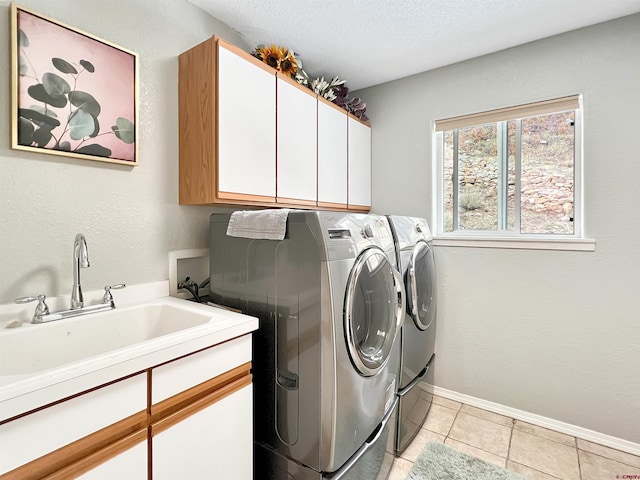 clothes washing area featuring sink, light tile patterned flooring, independent washer and dryer, cabinets, and a textured ceiling