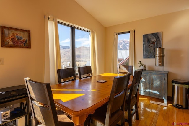 dining space with a mountain view, lofted ceiling, and light wood-type flooring