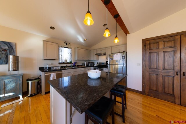 kitchen featuring vaulted ceiling with beams, a center island, hanging light fixtures, and stainless steel appliances