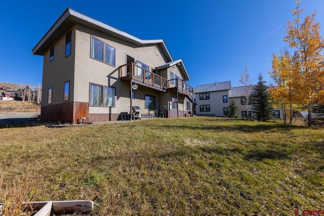 rear view of house with a yard and a balcony