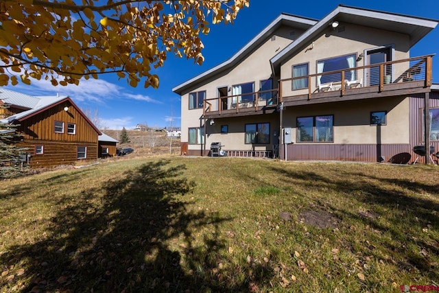 rear view of house featuring a yard and a balcony