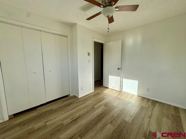 unfurnished bedroom with ceiling fan, a closet, a textured ceiling, and hardwood / wood-style flooring