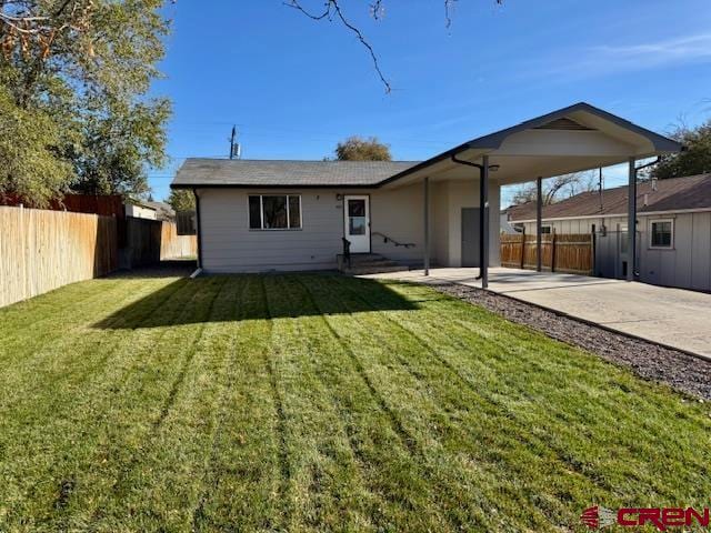 rear view of house featuring a lawn and a carport