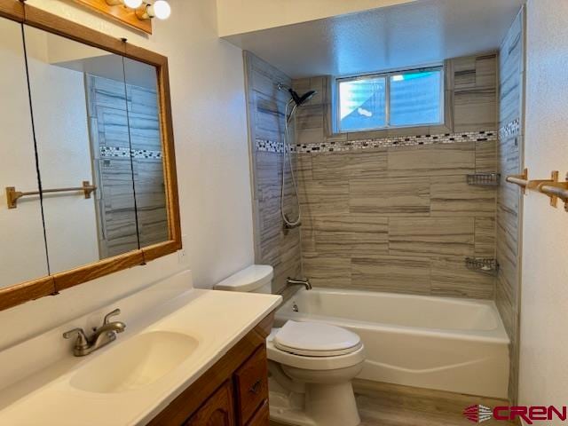 full bathroom featuring hardwood / wood-style floors, vanity, toilet, and tiled shower / bath