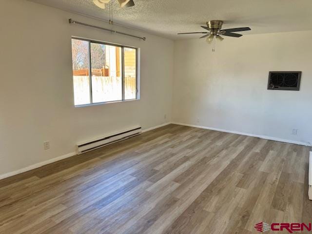 unfurnished room with a textured ceiling, ceiling fan, baseboard heating, and light hardwood / wood-style flooring