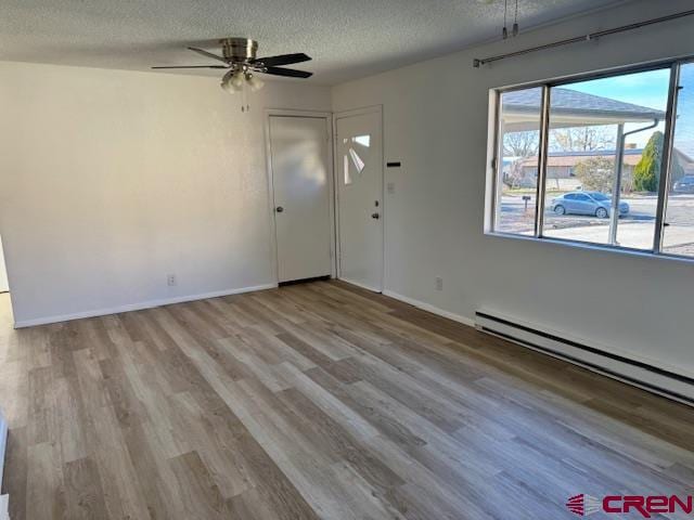 interior space with baseboard heating, ceiling fan, light hardwood / wood-style floors, and a textured ceiling