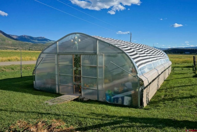 view of outdoor structure featuring a mountain view, a yard, and a rural view