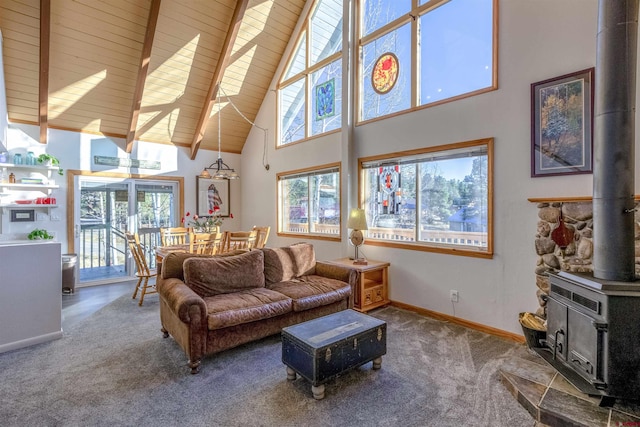 living room featuring beamed ceiling, a wood stove, carpet floors, and a towering ceiling