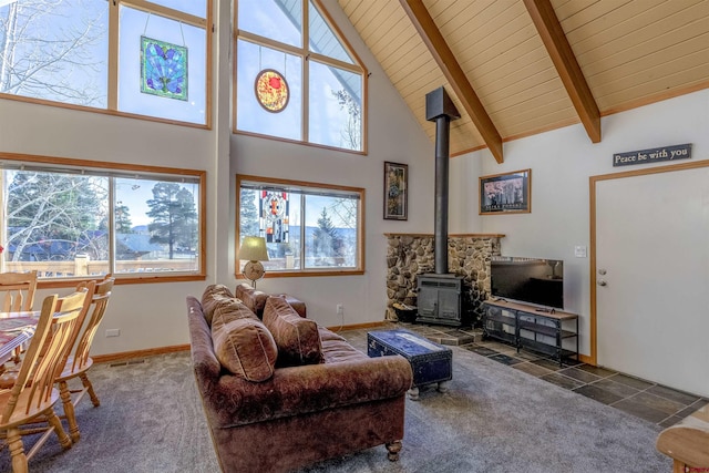 carpeted living room with beamed ceiling, high vaulted ceiling, a wood stove, and plenty of natural light