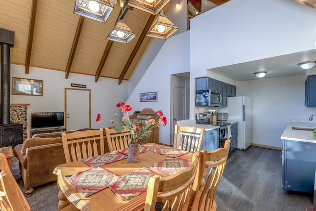 dining area with dark wood-type flooring, sink, high vaulted ceiling, beamed ceiling, and a wood stove