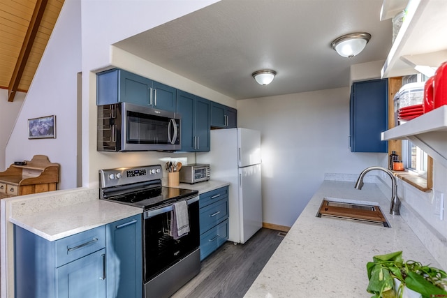 kitchen featuring blue cabinetry, sink, dark wood-type flooring, lofted ceiling with beams, and appliances with stainless steel finishes