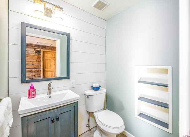 bathroom with wood walls, vanity, and toilet