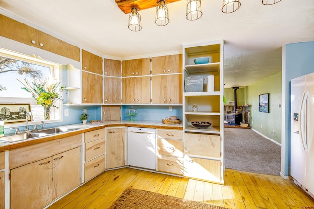 kitchen featuring light wood-type flooring, white appliances, sink, and a wood stove