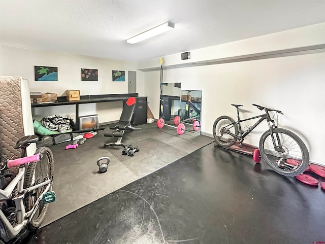 workout area featuring concrete flooring, a textured ceiling, and electric panel