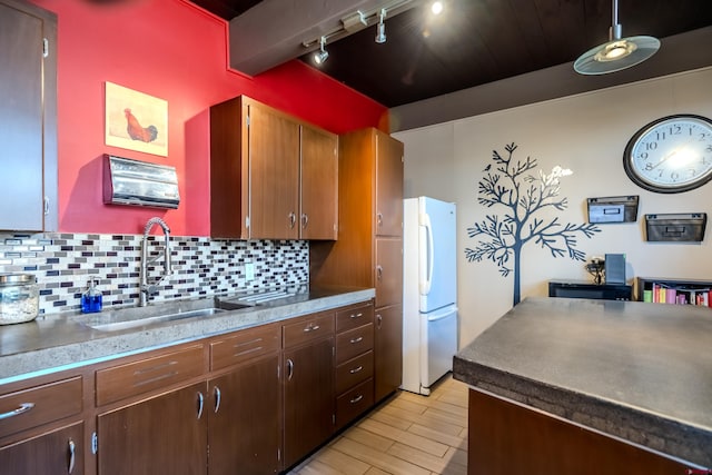 kitchen with rail lighting, backsplash, light hardwood / wood-style floors, sink, and white fridge