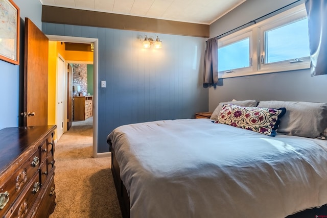 bedroom featuring light carpet and wooden walls