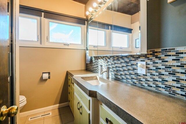 bathroom featuring tile patterned flooring, vanity, toilet, and backsplash