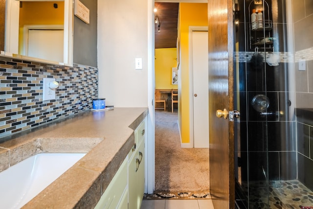 bathroom with tile patterned flooring, vanity, an enclosed shower, and backsplash